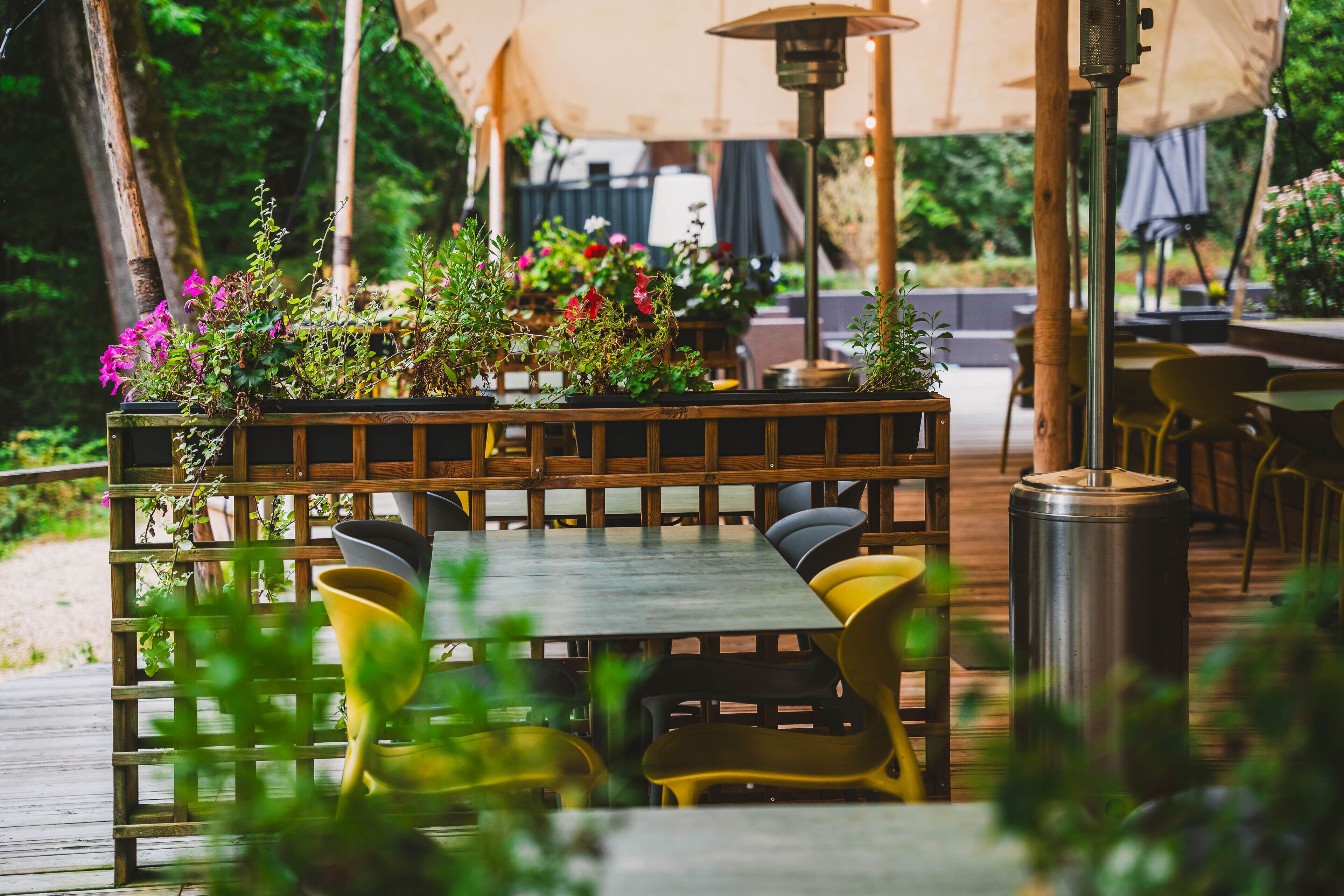 Un espace extérieur aménagé pour les repas, avec une terrasse en bois, des chaises jaunes et une table.