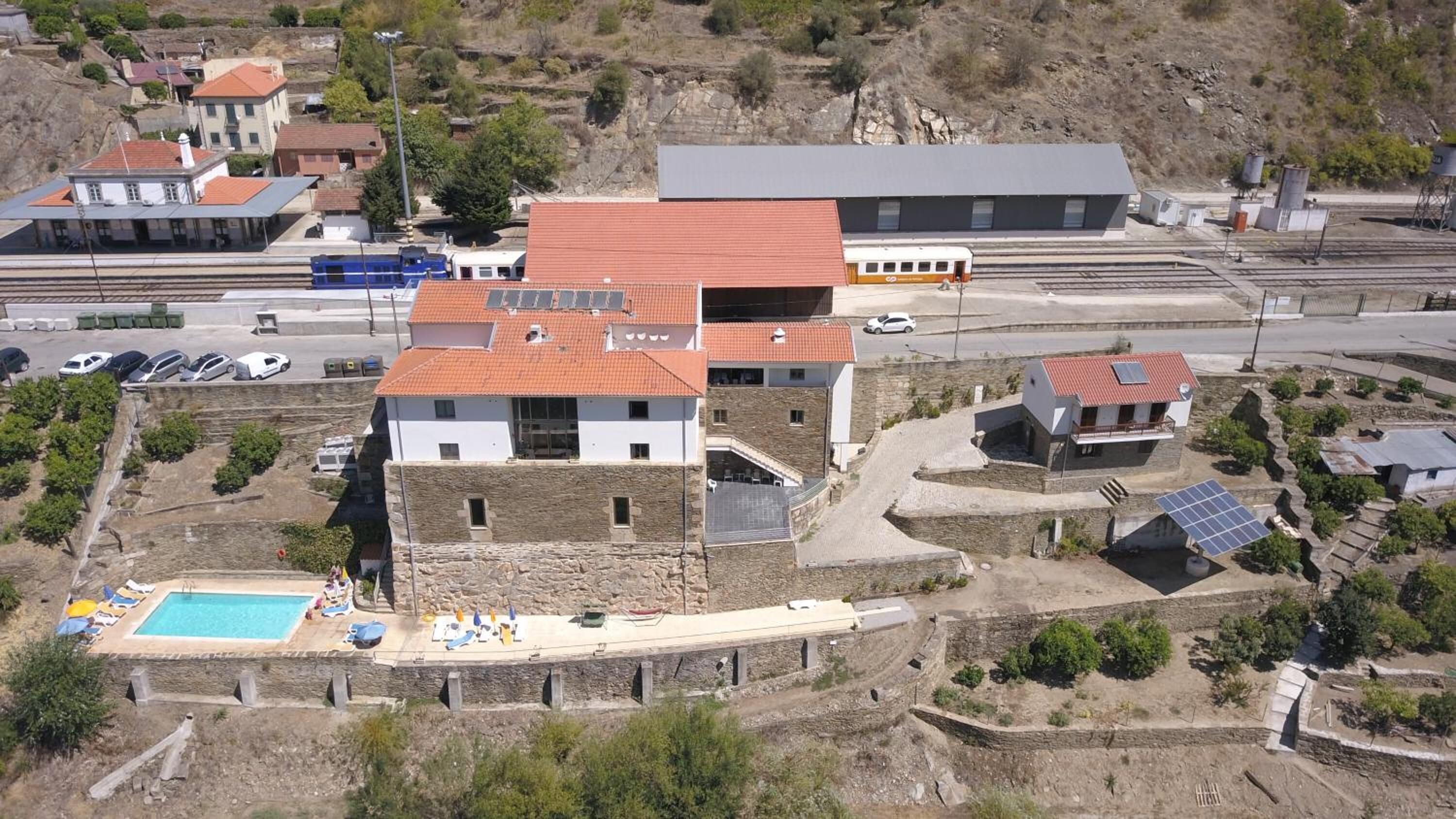 Un edificio moderno con tetto in tegole rosse, una piscina e una piccola barca.