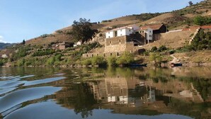 Propiedad a orillas del río con edificios de piedra, un muelle para barcos y un paisaje montañoso.