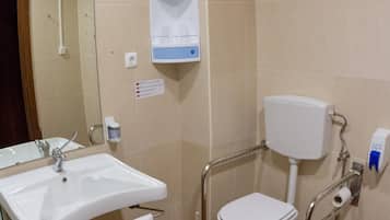 Un baño con lavamanos, inodoro y secador de manos.