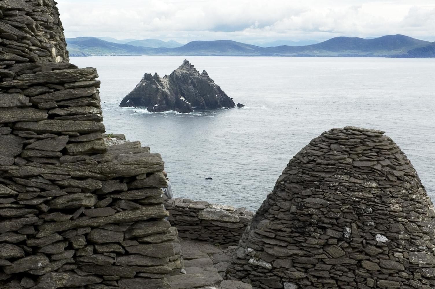 A stone structure with a view of a distant island and mountains.