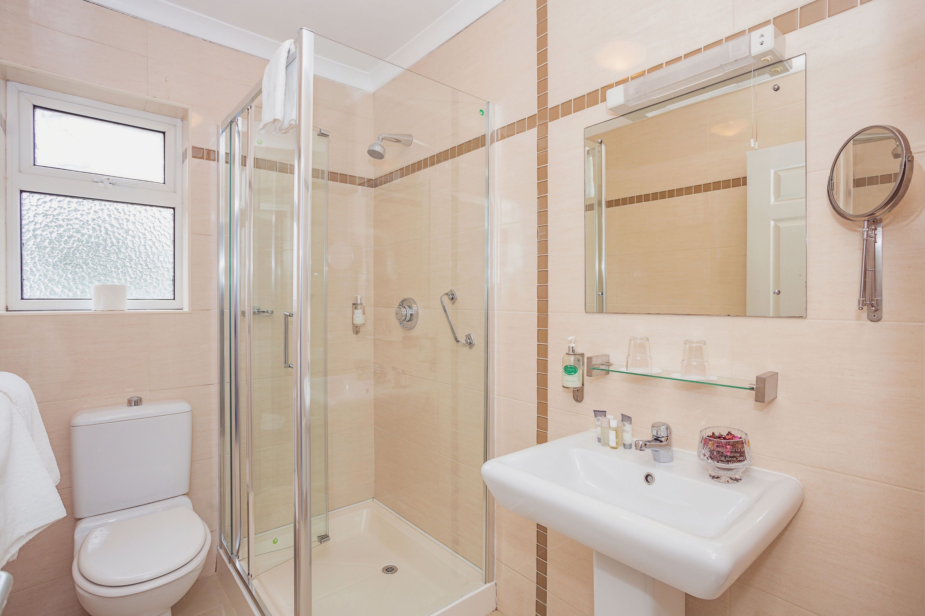 A modern bathroom with a glass-enclosed shower, a white sink with a mirror, and a toilet.