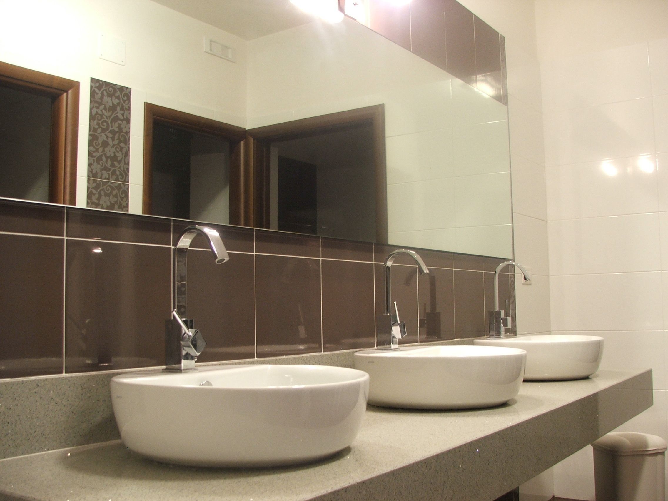 A bathroom with three sinks and a large mirror.