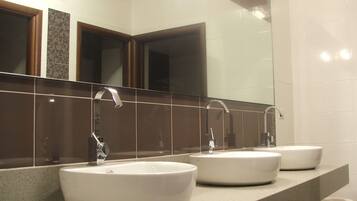 A bathroom with three sinks and a large mirror.