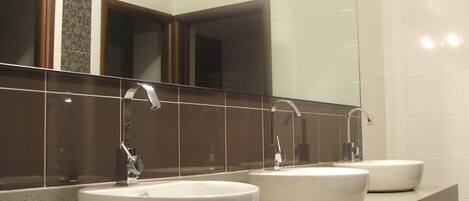 A bathroom with three sinks and a large mirror.