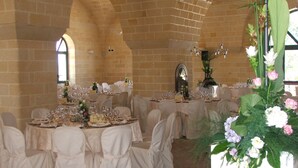 Un salón de banquetes con mesas redondas dispuestas para un evento formal, con manteles blancos y sillas.