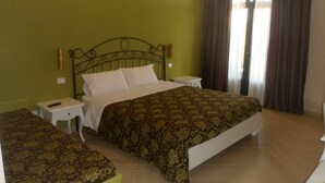 Habitación de hotel con cama, dos mesitas de noche y una ventana con cortinas.
