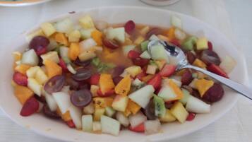 Un tazón de ensalada de frutas con una cuchara.