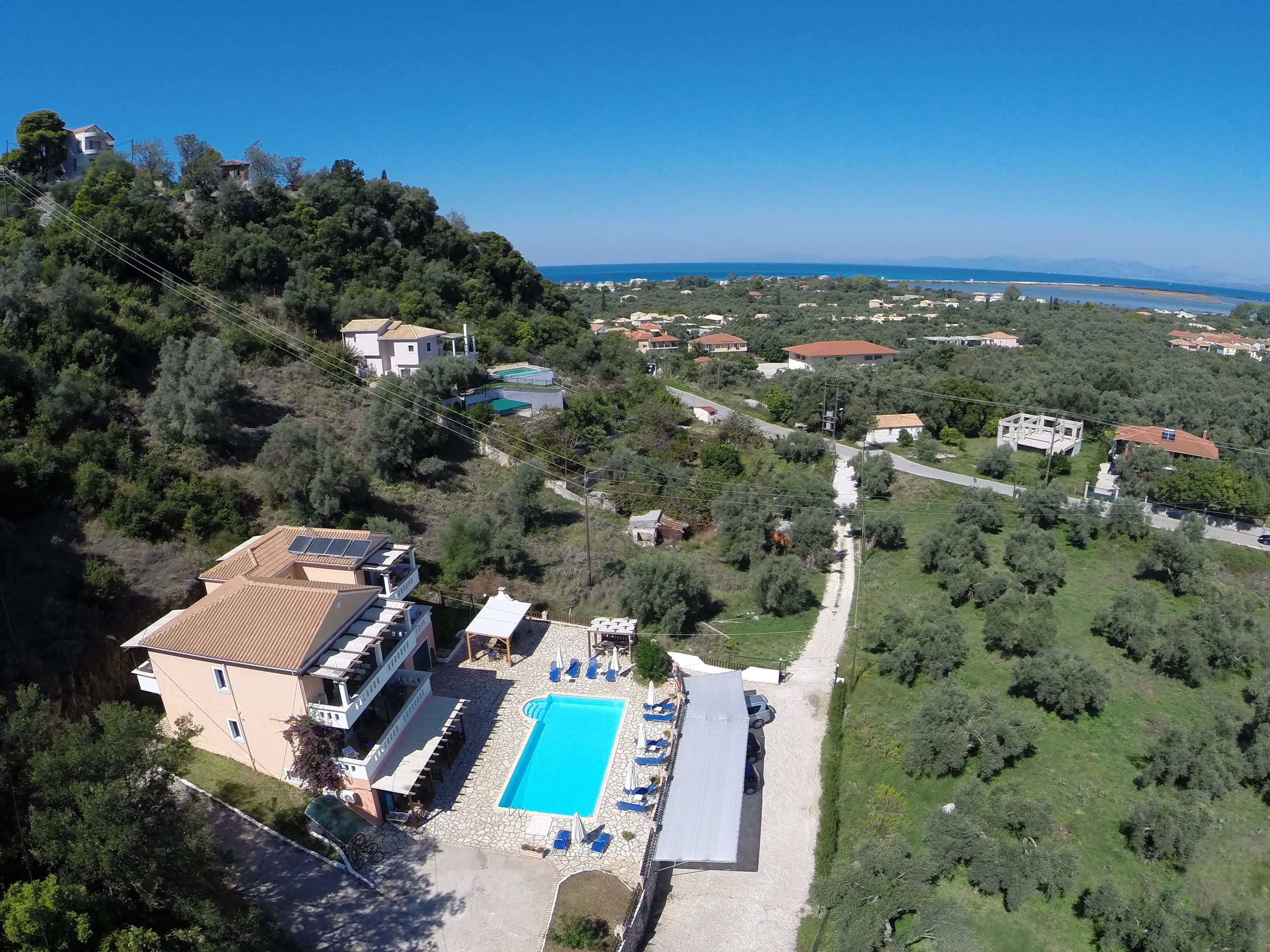An aerial view of a property with a swimming pool, a covered patio, and a view of the sea.