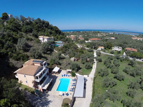 An aerial view of a property with a swimming pool, a covered patio, and a view of the sea. - Apartments Ithaki Holidays (Lefkada)