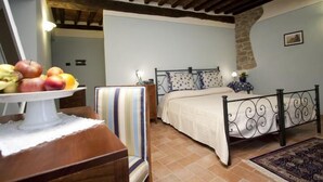Ein Schlafzimmer mit einem Bett, einem Sessel, einem Tisch mit Obst und einer Steinwand.