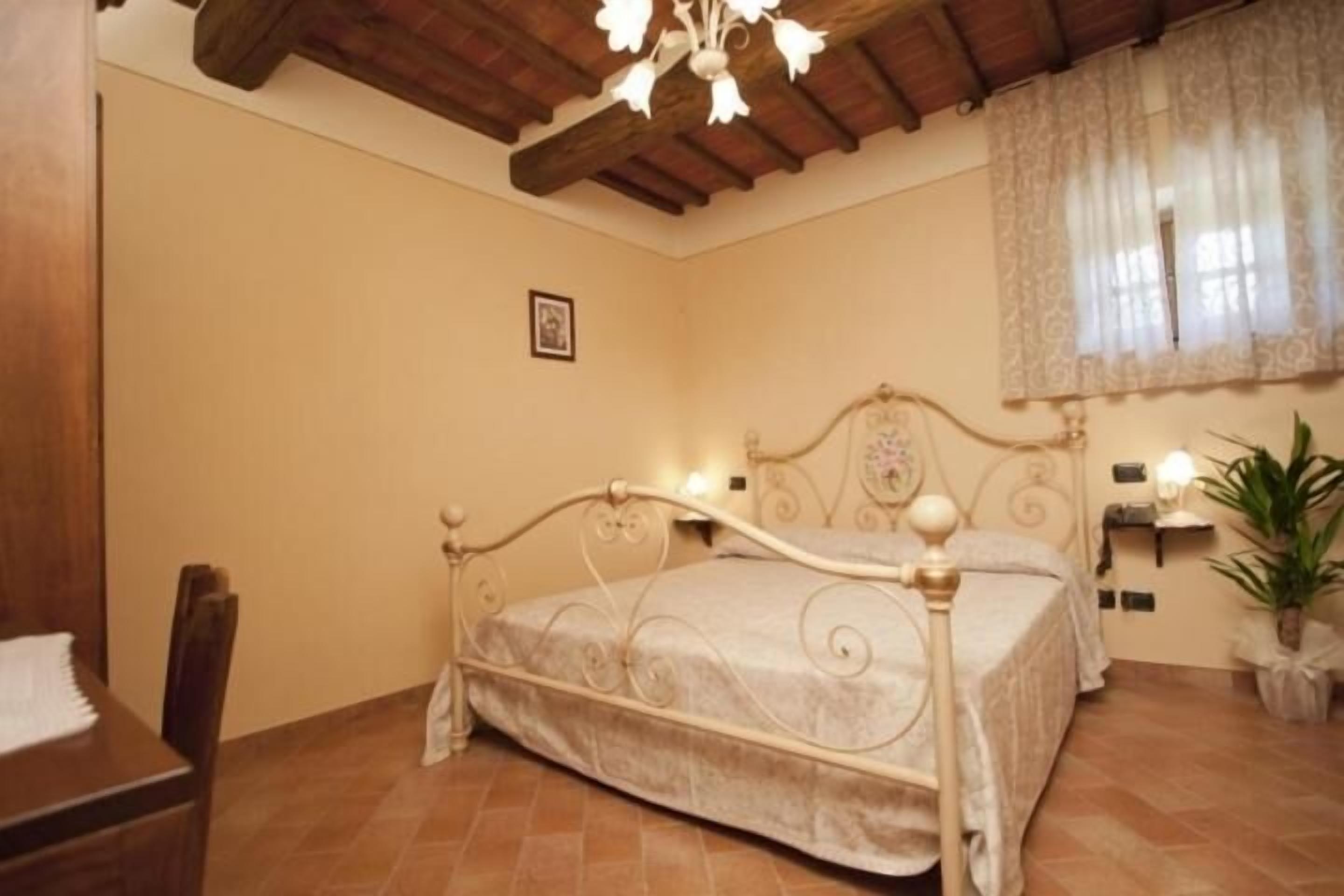 A bedroom with a bed, a chair, a desk, a window with curtains, and a ceiling fan.