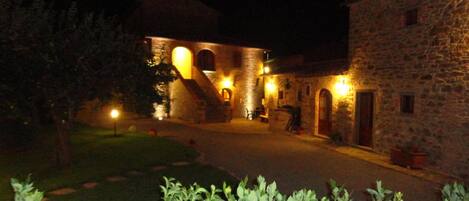 Un edificio de piedra con una escalera central y aberturas en arco, rodeado por un patio bien iluminado.