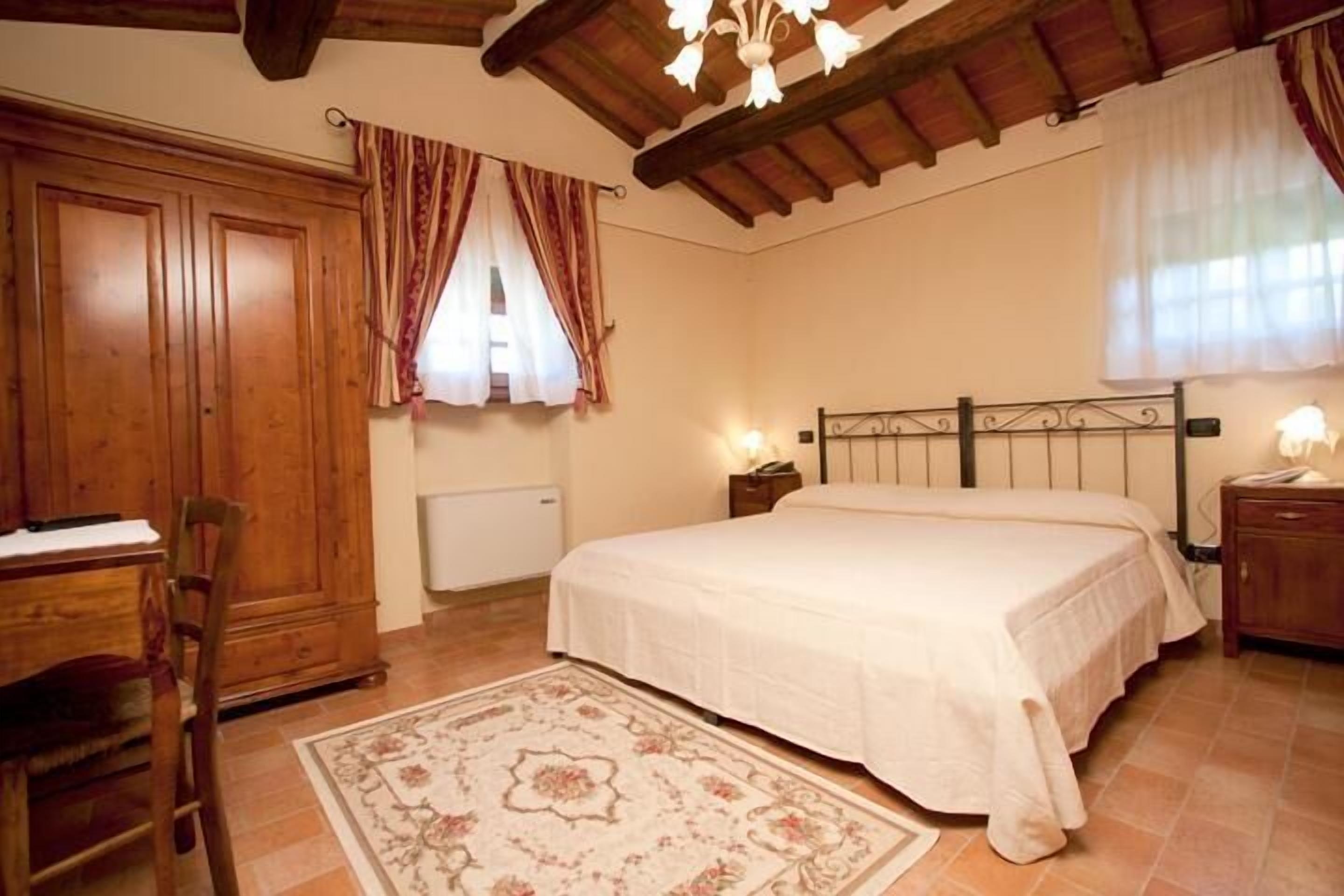 Ein Schlafzimmer mit Bett, Holzschrank, Schreibtisch, Stuhl und Heizkörper.