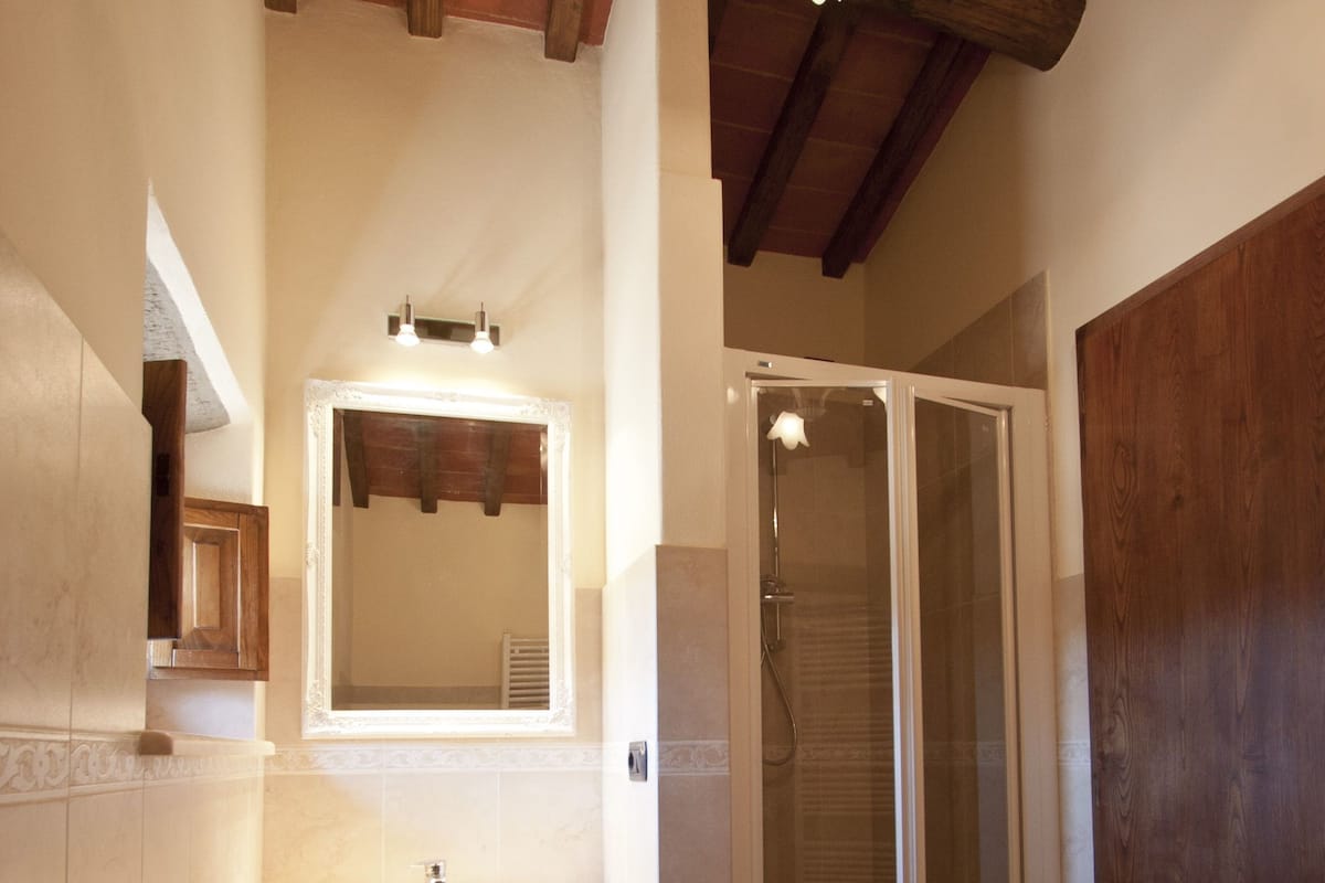 Un baño con tocador de madera, lavamanos, espejo, cabina de ducha y bañera.
