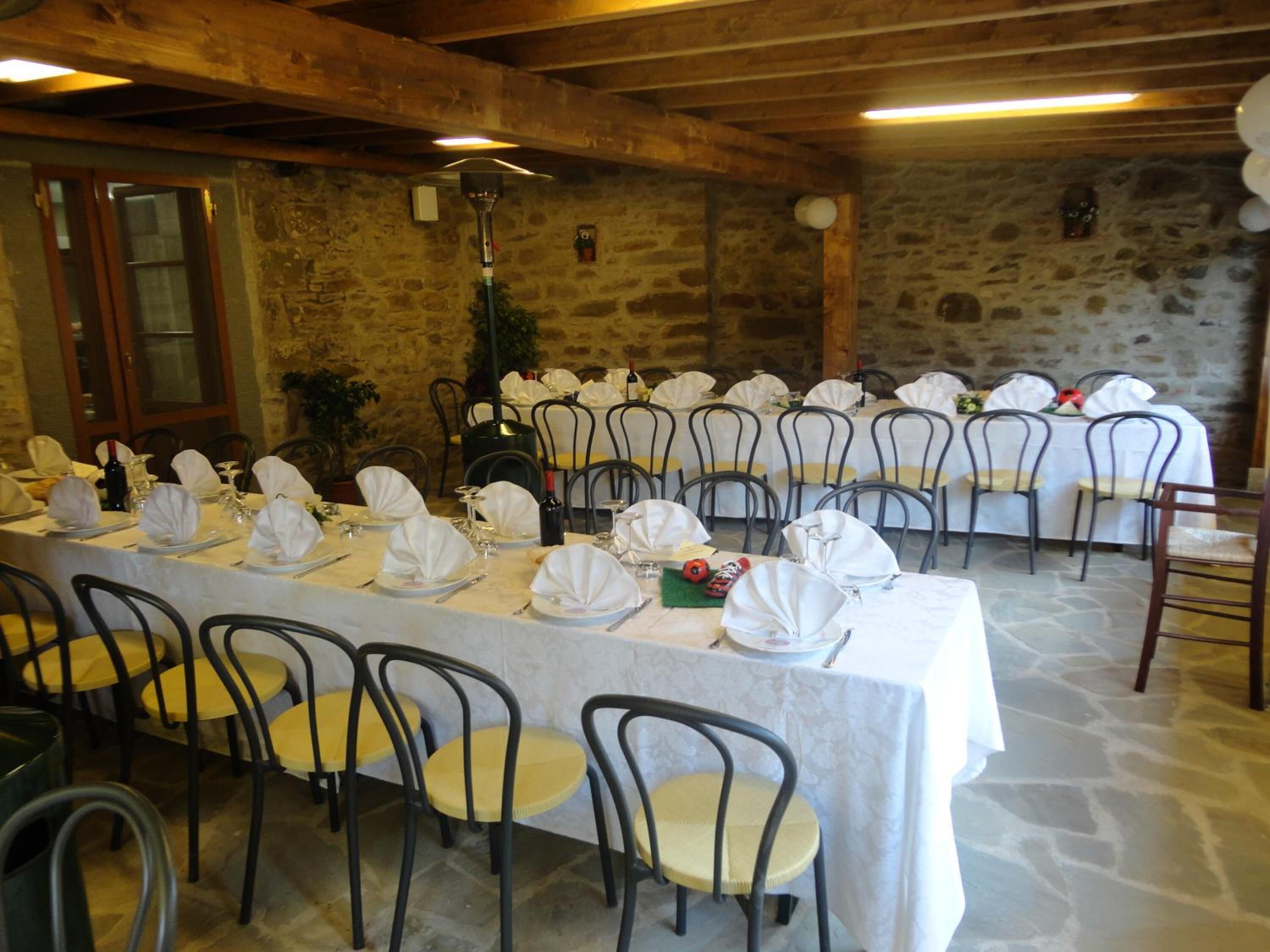 Une longue table de banquet, recouverte de nappes blanches, avec des chaises et une décoration de table comprenant des assiettes, des verres et des couverts.