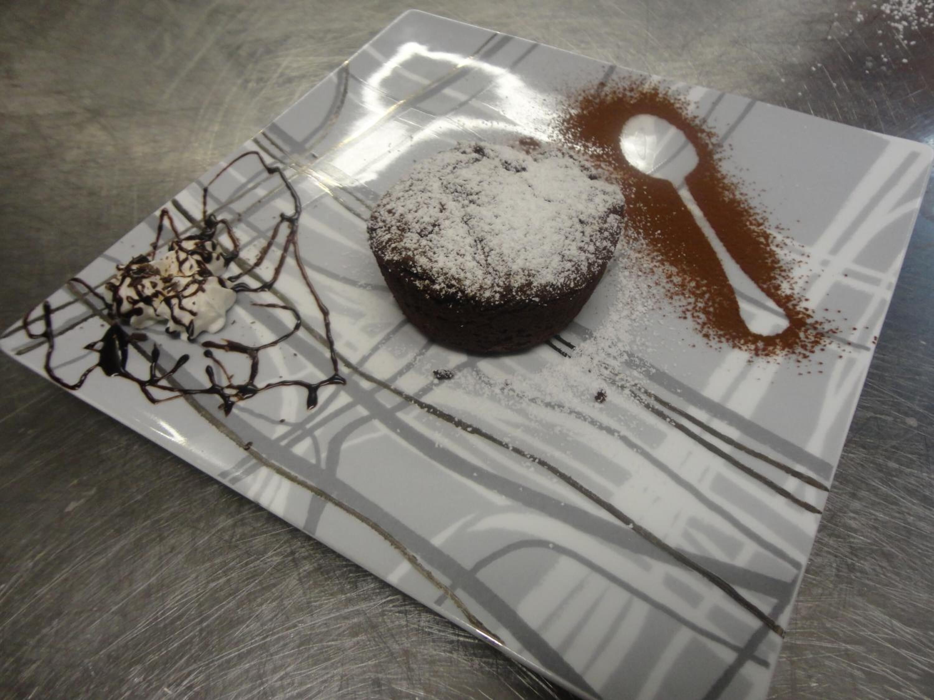 Een dessert op een bord met poedersuiker en chocoladesiroop.