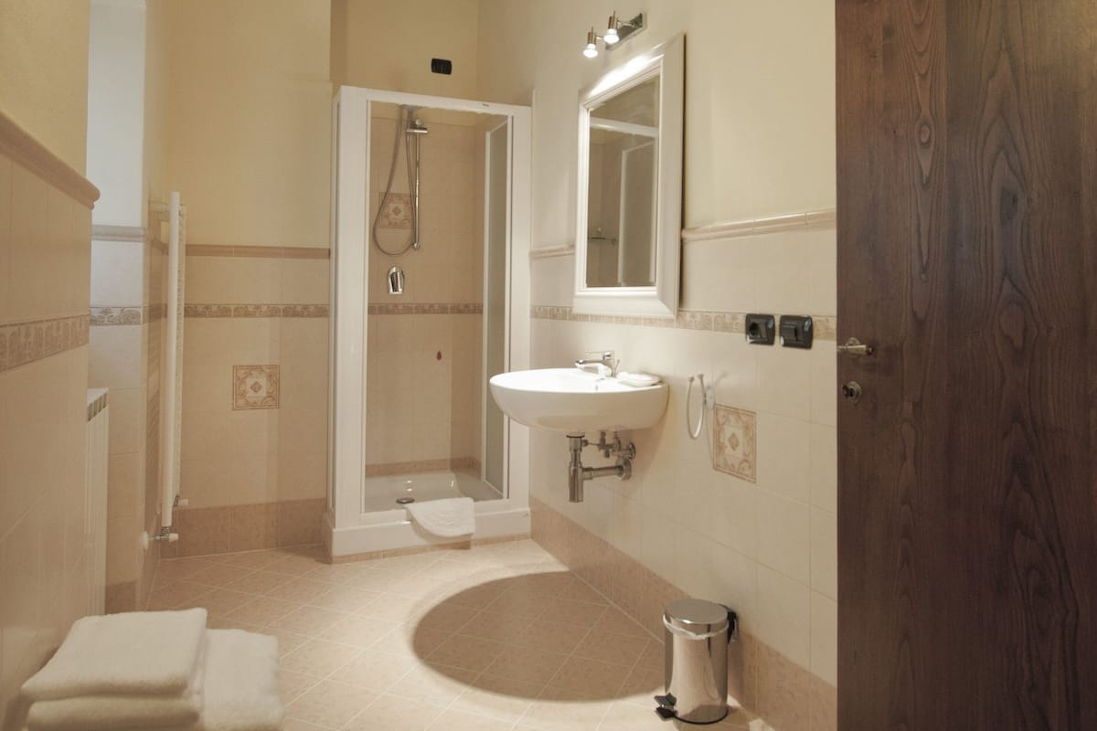 Un baño con ducha, lavamanos y puerta de madera.