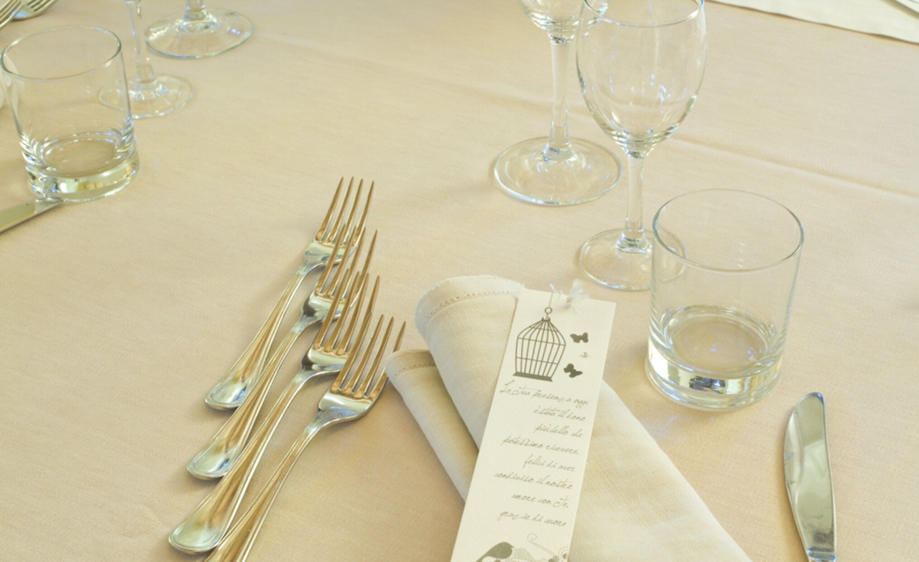 Una mesa servida con cubiertos, vasos y una carta.