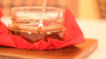 A jar of jam with a spoon inside, placed on a wooden surface with a red cloth underneath.