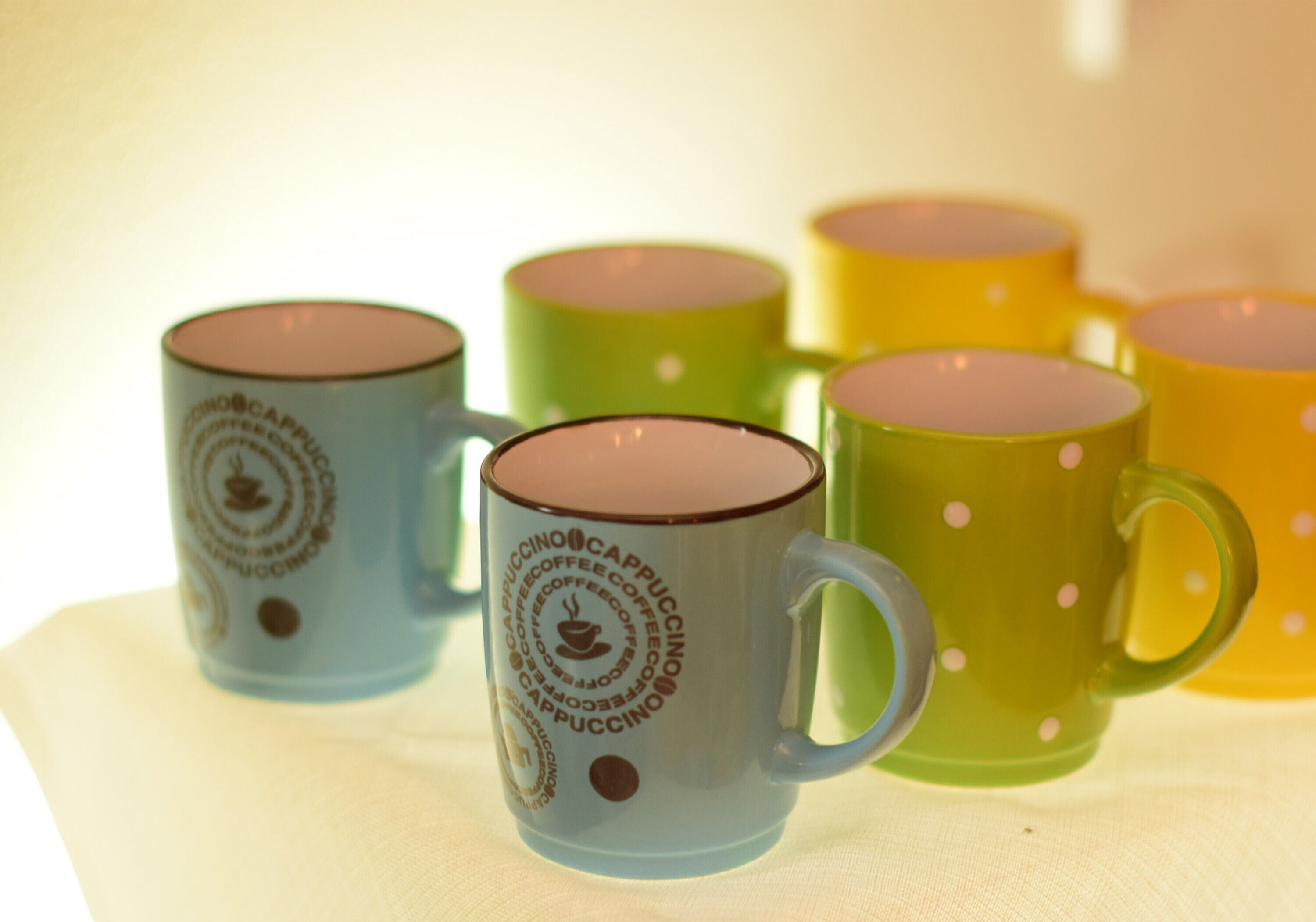 A collection of colorful coffee mugs with text and logos, arranged on a surface.