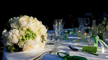 A table set for a formal event with a floral centerpiece, clear glassware, and a green ribbon.