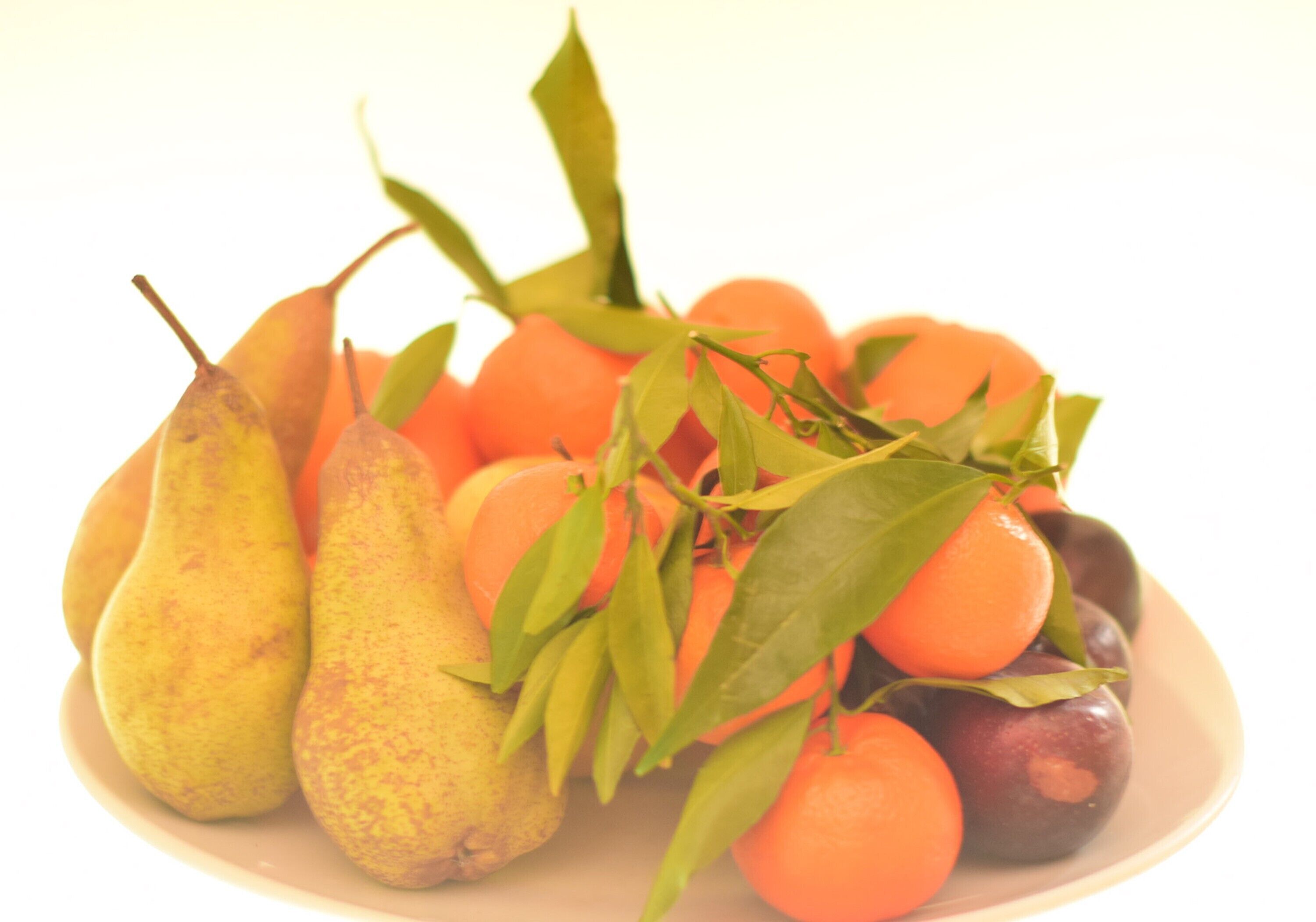 A plate of fruits including pears and oranges.