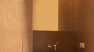 Un baño moderno con un espejo grande, un lavabo blanco y un perchero para toallas.