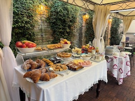 Una mesa de buffet con diferentes alimentos y un fondo de vegetación y paredes de piedra.