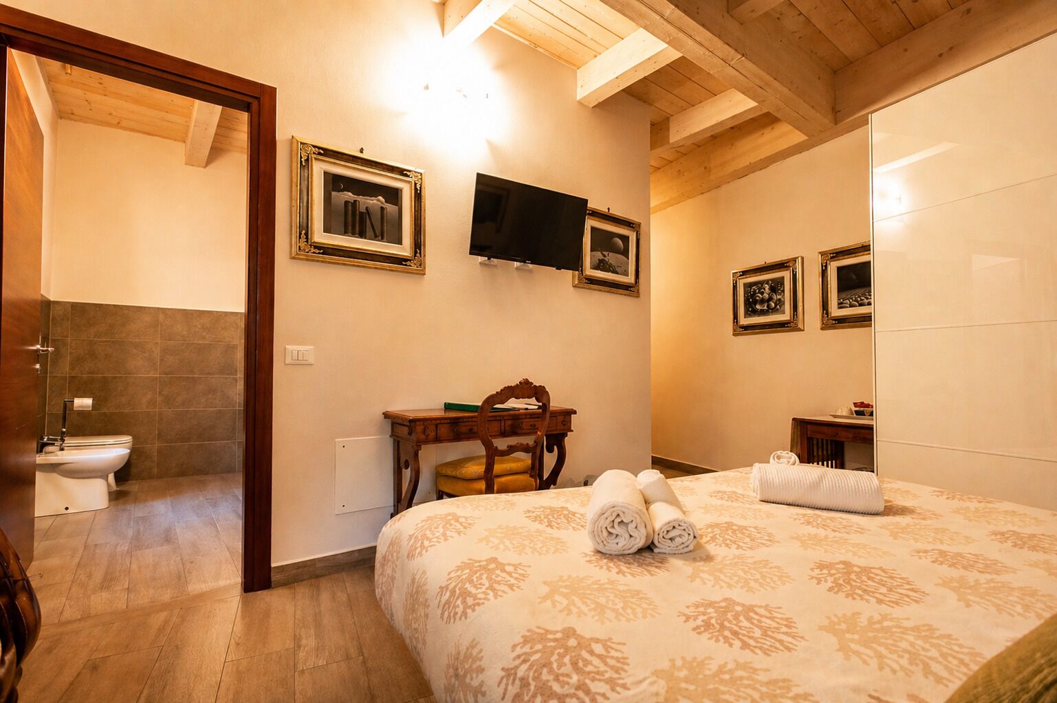 A hotel room with a bed, a desk, a chair, a television, and a bathroom.