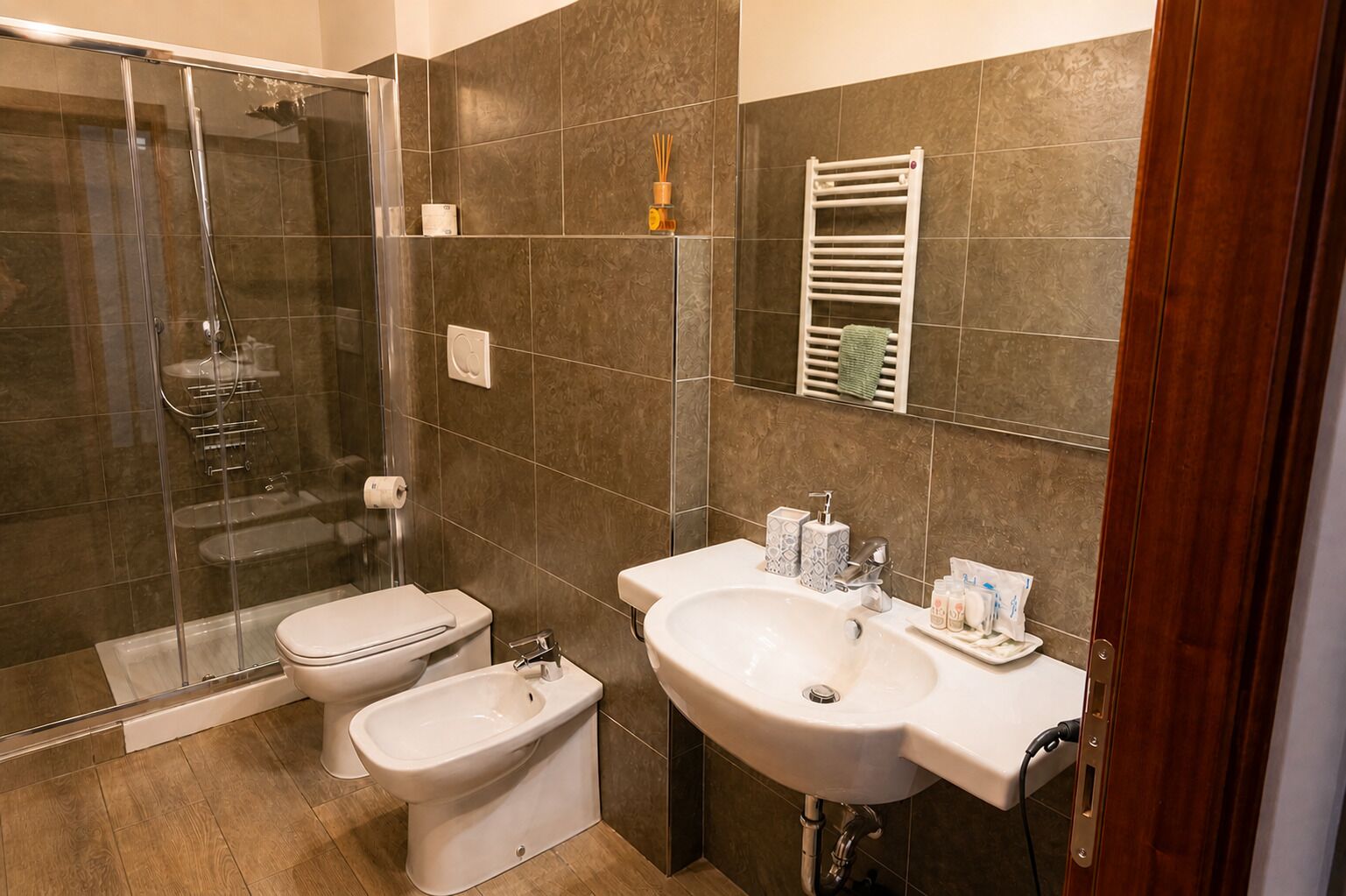A bathroom with a glass-enclosed shower, a toilet, a bidet, and a sink with toiletries.