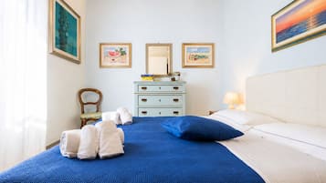 A bedroom with a bed, a dresser, a chair, and artwork on the walls.