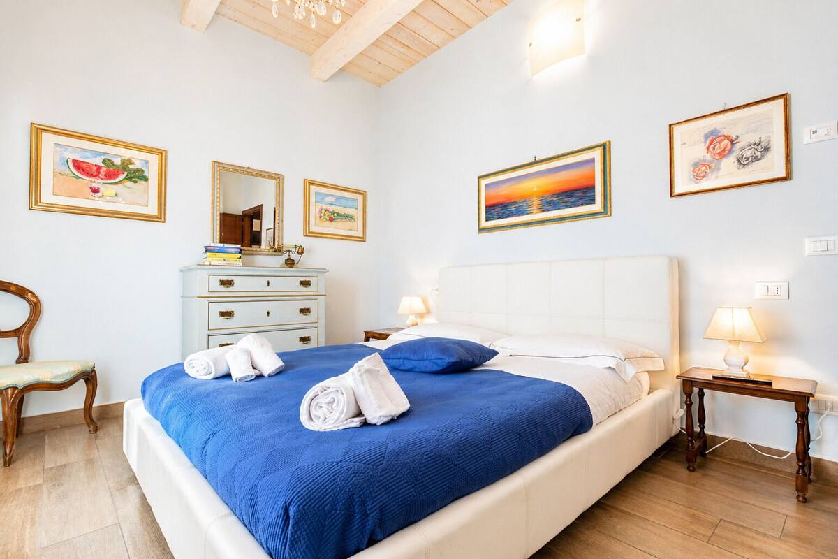 A bedroom with a bed, a dresser, a chair, and artwork on the walls.