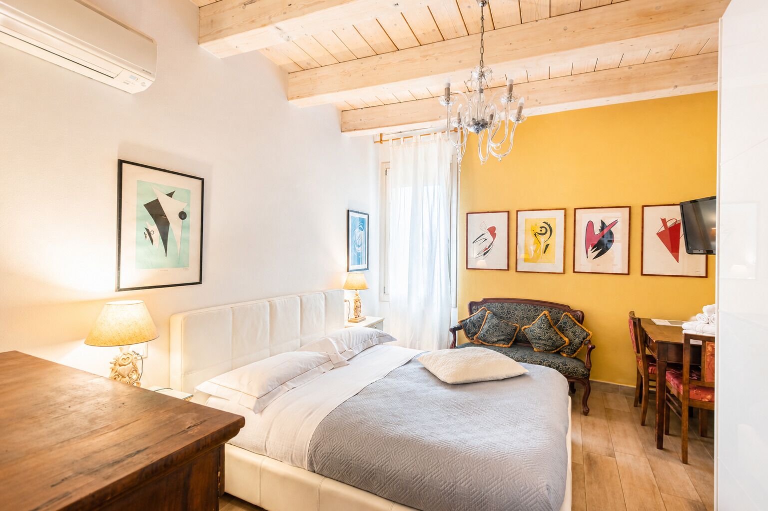 Une chambre à coucher avec un lit, une table en bois, un canapé et un téléviseur.