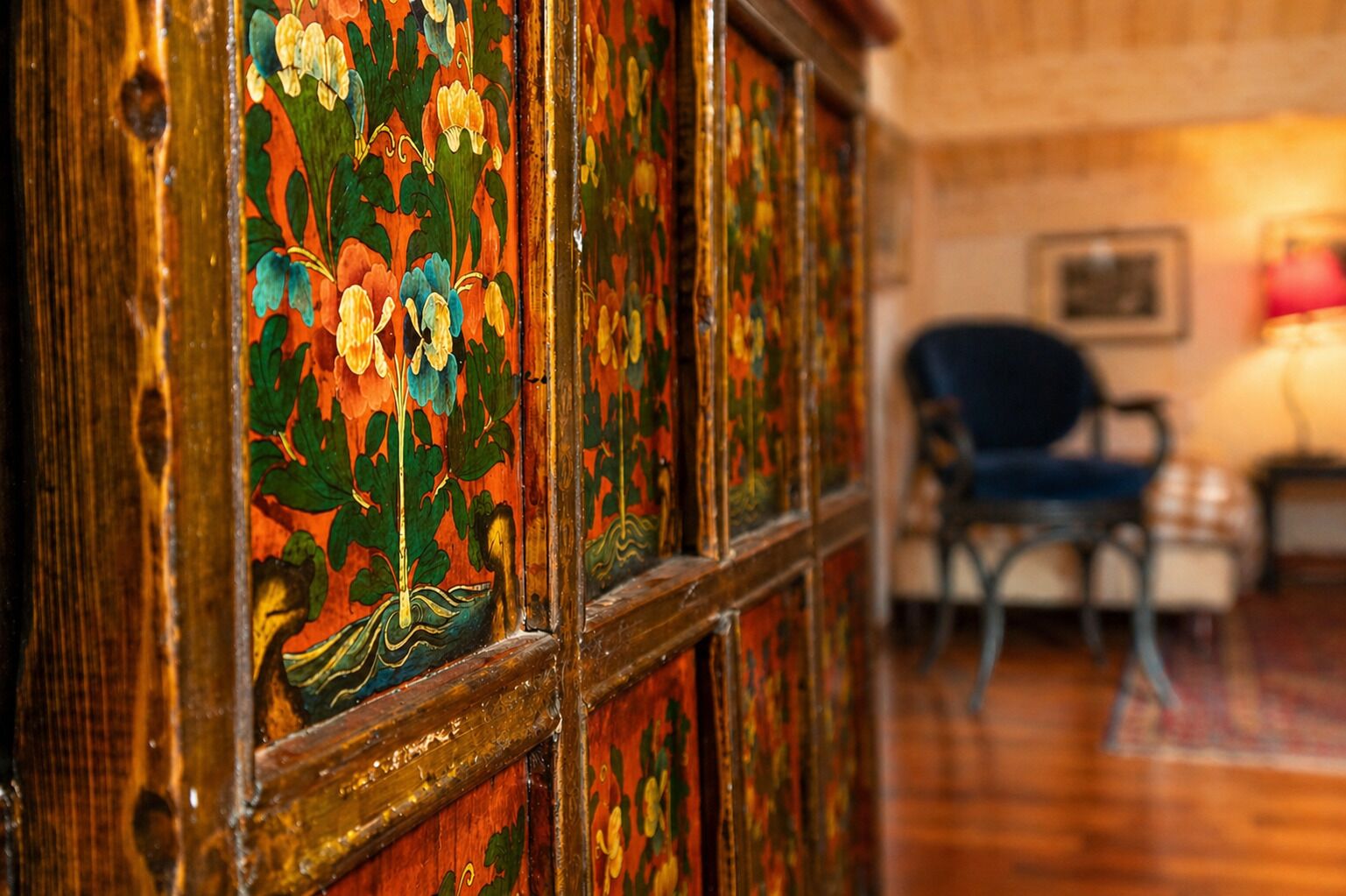Un mur lambrissé en bois orné de motifs floraux, une chaise et un lit à l’arrière-plan.