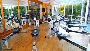 Un gimnasio con diferentes máquinas de ejercicio, espejos amplios y suelo de madera.