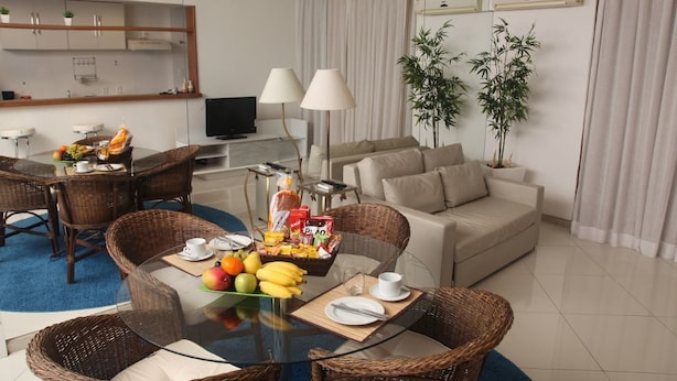 Una habitación de hotel moderna con comedor, sofá y televisión.