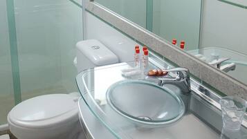 A modern bathroom with a glass shower enclosure, a white toilet, a glass sink, and a large mirror.