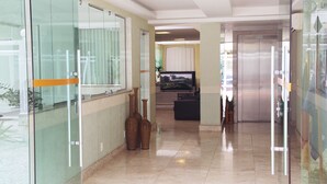 Un pasillo moderno en un hotel, con paredes de vidrio, un televisor de pantalla plana y un piso de baldosas limpias.