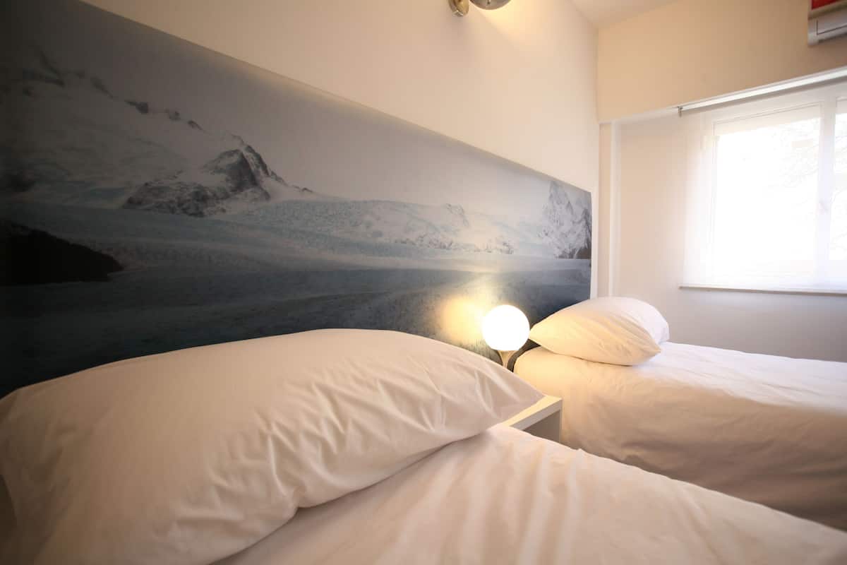 Un dormitorio con dos camas, un mural de montaña y una lámpara de noche.
