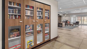 A library with bookshelves and a reading area with tables and chairs. - Candlewood Suites Alexandria by IHG (Alexandria)