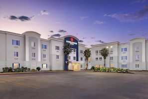 A hotel with a prominent entrance, multiple floors, and a parking lot.