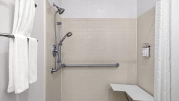 Une douche équipée d’une barre d’appui, d’un porte-serviettes et d’une étagère pour les articles de toilette.