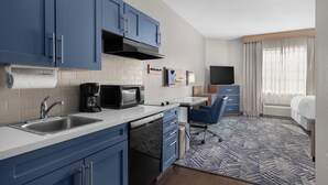 A compact hotel room with a kitchenette, a bed, a TV, and a bathroom. - Candlewood Suites Alexandria by IHG (Alexandria)