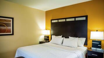 A hotel room with a large bed, two bedside tables, a nightstand, and a framed picture on the wall.