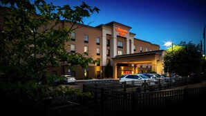Ett Hampton Inn-hotell med en parkeringsplats och en väl upplyst entré.