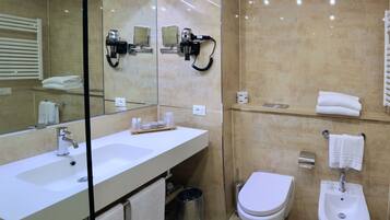 Un baño moderno con un espejo grande, un lavamanos blanco, un inodoro y un bidé.