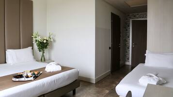 Habitación de hotel con dos camas, una bandeja de desayuno, un jarrón de flores y una puerta que da a otra habitación.