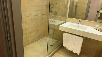 A modern bathroom with a glass-enclosed shower, a white sink, and a large mirror.