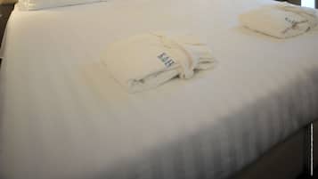 Une chambre d’hôtel avec un grand lit, deux oreillers, une table de chevet avec une lampe et une fenêtre avec des rideaux.
